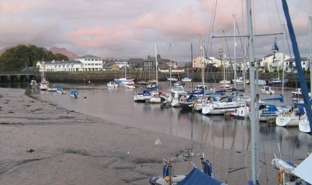 porthmadog harbour, small boats and yachts sit on the mud with buildings in the background